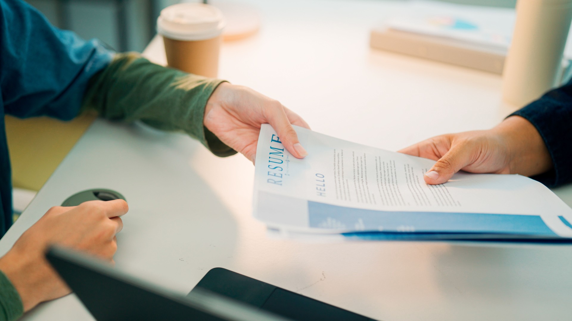 Young Asian man handing his résumé to HR officer at the beginning of the interview.